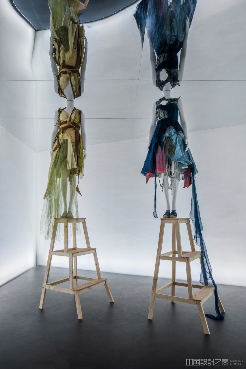 Mannequins dressed in Hussein Chalayan are positio<em></em>ned on step ladders below a mirrored ceiling