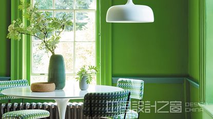 Bold green dining room with white pedestal dining table and pendant light