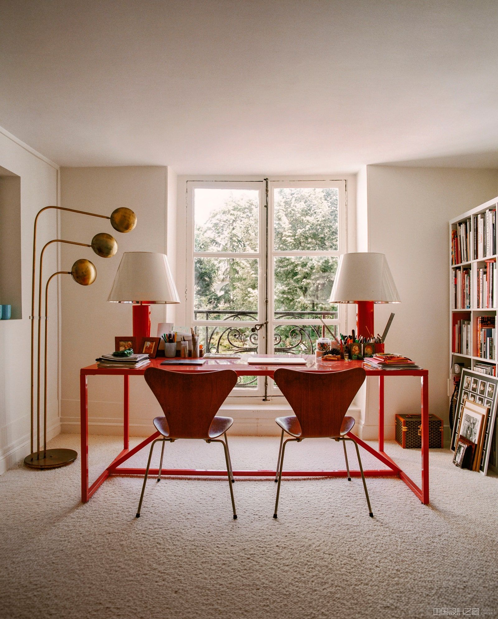 office with a red desk red lamps bookshelves window