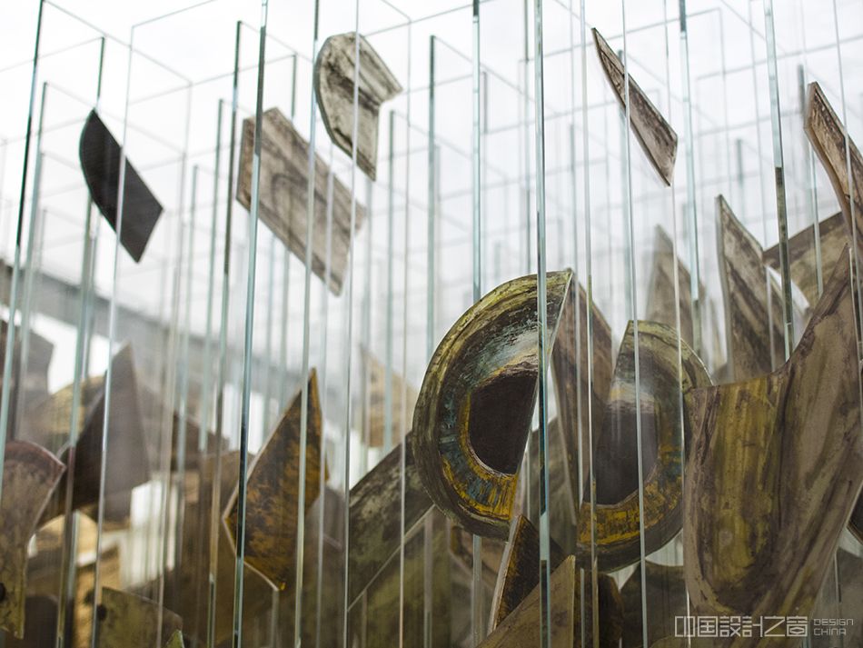 A detail of a sculpture in a glass and me<em></em>tal cube on a co<em></em>ncrete stand, co<em></em>ntaining more than 144 strips of glass that looks like a different animal on each side.