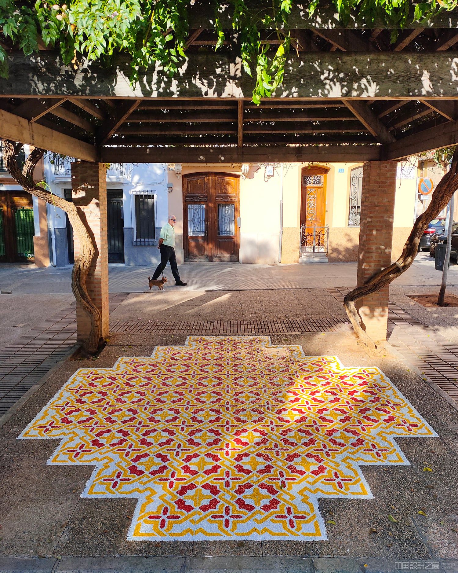 A photo of a vibrant patterned rug-like intervention painted on the co<em></em>ncrete in a city