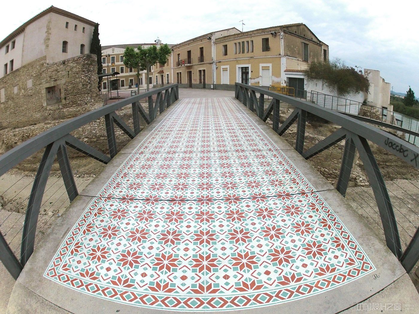 A photo of a vibrant patterned rug-like intervention painted on the co<em></em>ncrete in a city